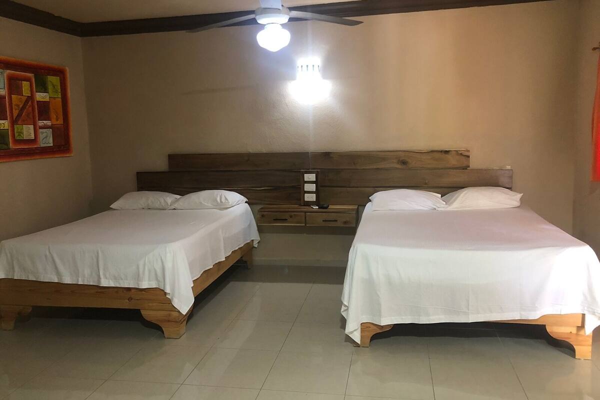 A room with two wooden beds, a ceiling fan, and a wall-mounted light fixture.