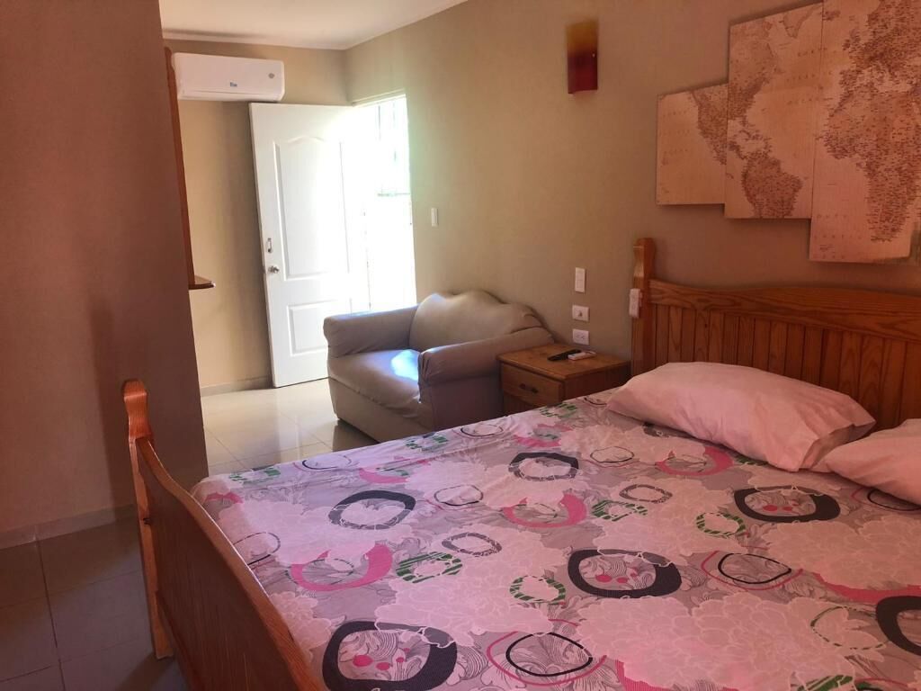 A bedroom with a bed, a chair, a nightstand, and a wall-mounted map.