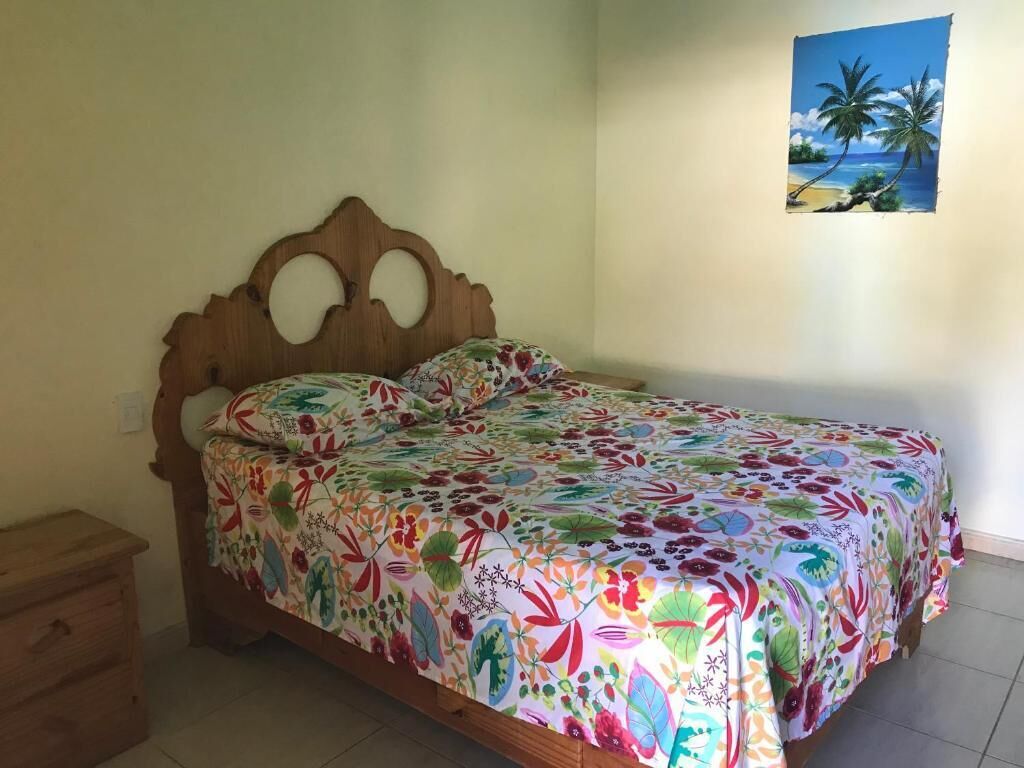 A bed with a floral bedspread, a wooden headboard, and a small wooden nightstand.