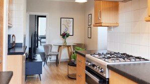 Una cocina moderna con estufa a gas, armarios de madera y un comedor con mesa y sillas.