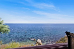 A coastal view with clear water, rocks, and a distant horizon.