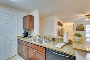 A kitchen with granite countertops, wooden cabinets, a dishwasher, and a double sink. - PCB Condo w/ Pool Access: 1 Mi to Beach! (Panama City Beach)