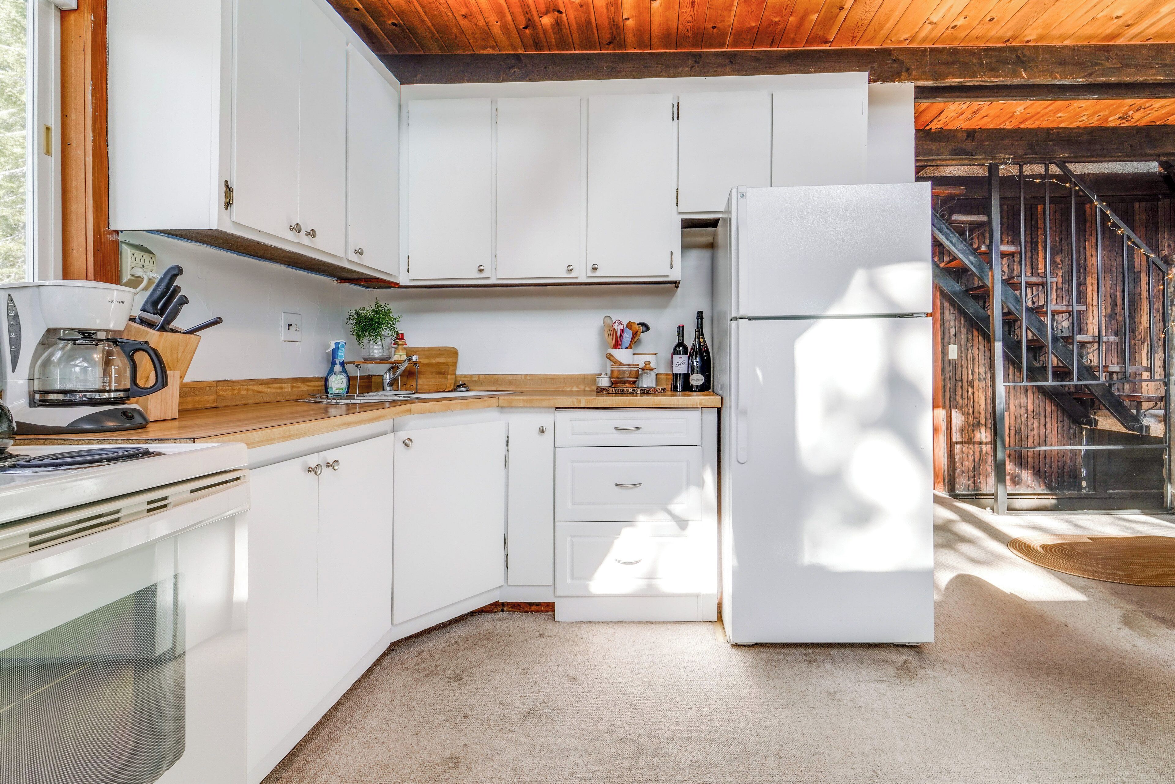 A modern kitchen with white cabinets, a wooden countertop, and a built-in oven.