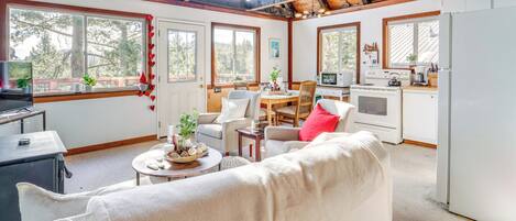 Una sala de estar acogedora con sofá, una mesa de comedor y una zona de cocina con estufa y refrigerador.