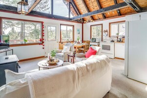 Una sala de estar acogedora con sofá, una mesa de comedor y una zona de cocina con estufa y refrigerador.