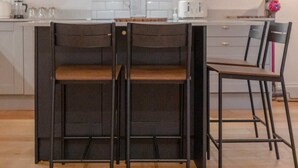 A modern kitchen with a central island, pendant lights, and grey cabinetry. - Newly Refurbished 2BD Flat - Wimbledon Village! (London)