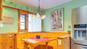 Une cuisine dotée de meubles en bois, d’une banquette intégrée, d’un réfrigérateur en acier inoxydable et d’un lustre en vitrail.