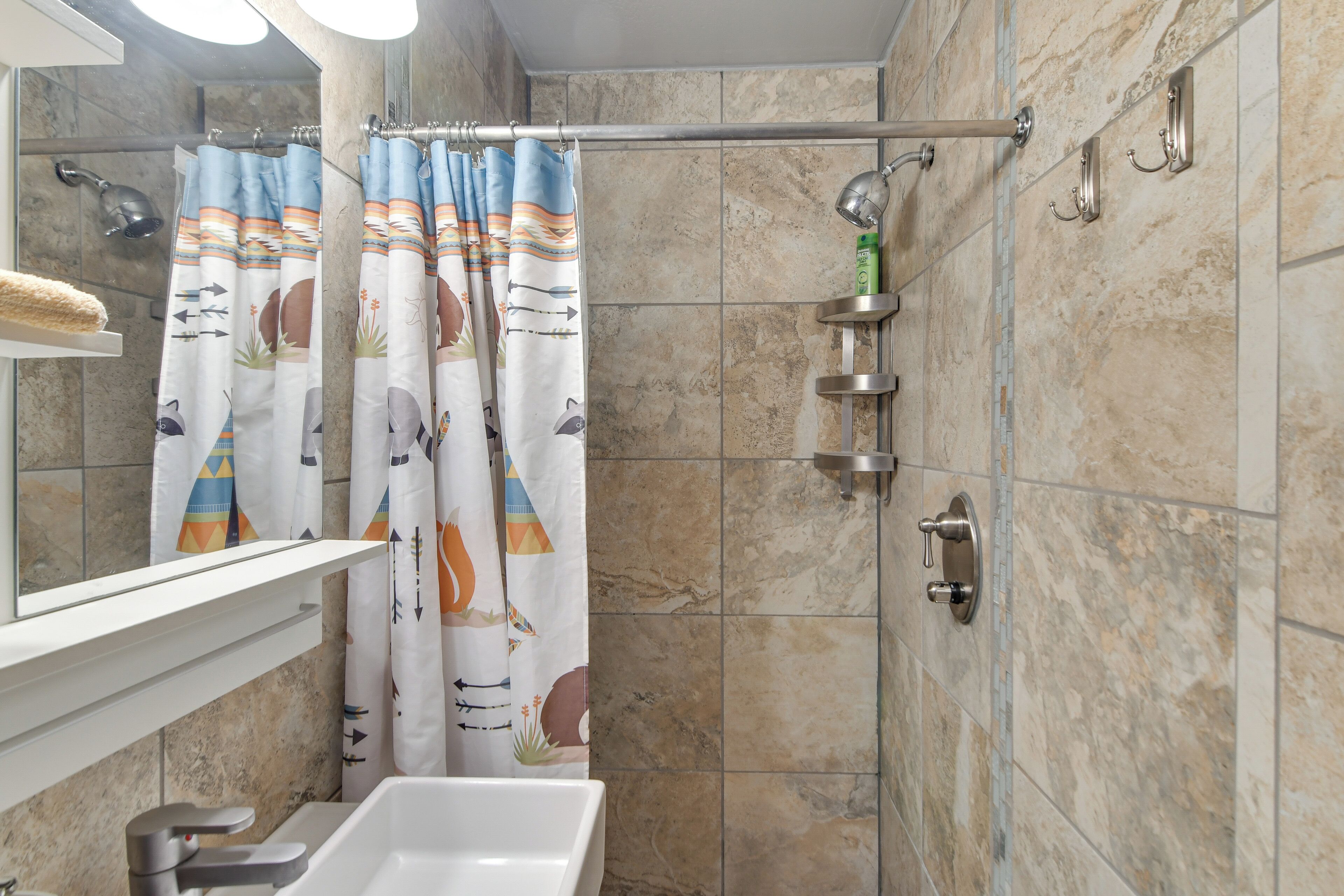Une salle de bain équipée d’une douche, d’un lavabo, d’un miroir et d’un porte-serviettes.