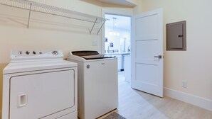 Pesutila, jossa on pesukone ja kuivausrumpu, pyykkiteline ja ovi, joka johtaa keittiöön.