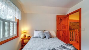 Een slaapkamer met een bed, nachtkastje, lamp en een houten deur die uitkomt op een balkon.