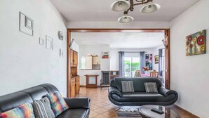 A living room with two black leather sofas, a glass coffee table, and a dining area in the background. - Villa Ninos - Three Bedroom Villa, Sleeps 6 (Albufeira)