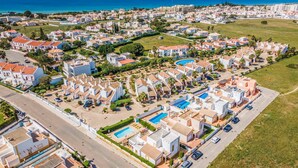 An aerial view of a coastal residential area with houses, a swimming pool, and a road. - Villa Ninos - Three Bedroom Villa, Sleeps 6 (Albufeira)