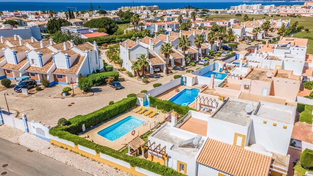 A coastal residential area with white buildings, a swimming pool, and a beach. - Villa Ninos - Three Bedroom Villa, Sleeps 6 (Albufeira)