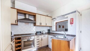 A compact kitchen with a built-in oven, a microwave, and a coffee maker. There is a small sink and a cabinet with wine storage. - Villa Ninos - Three Bedroom Villa, Sleeps 6 (Albufeira)