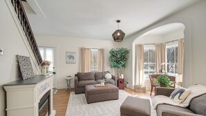 A living room with a fireplace, a sofa, a coffee table, and a dining area with a table and chairs. - Peninsula Paradise - Walk to Hiking & Shopping! (Peninsula)