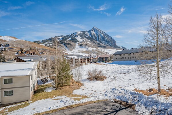 Zona residencial con suelo cubierto de nieve, una montaña al fondo y edificios con techos planos.