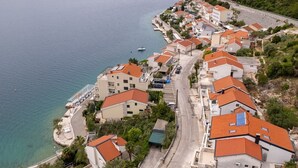 Una zona residencial costera con casas a lo largo de la orilla, con balcones y una calle pavimentada.