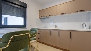 Una cocina moderna con armarios color beige, una encimera blanca y una silla verde.