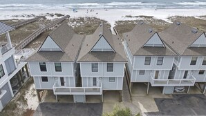 Une propriété située en bord de mer, comprenant des bâtiments à plusieurs étages, une promenade en bois et offrant une vue sur la plage.