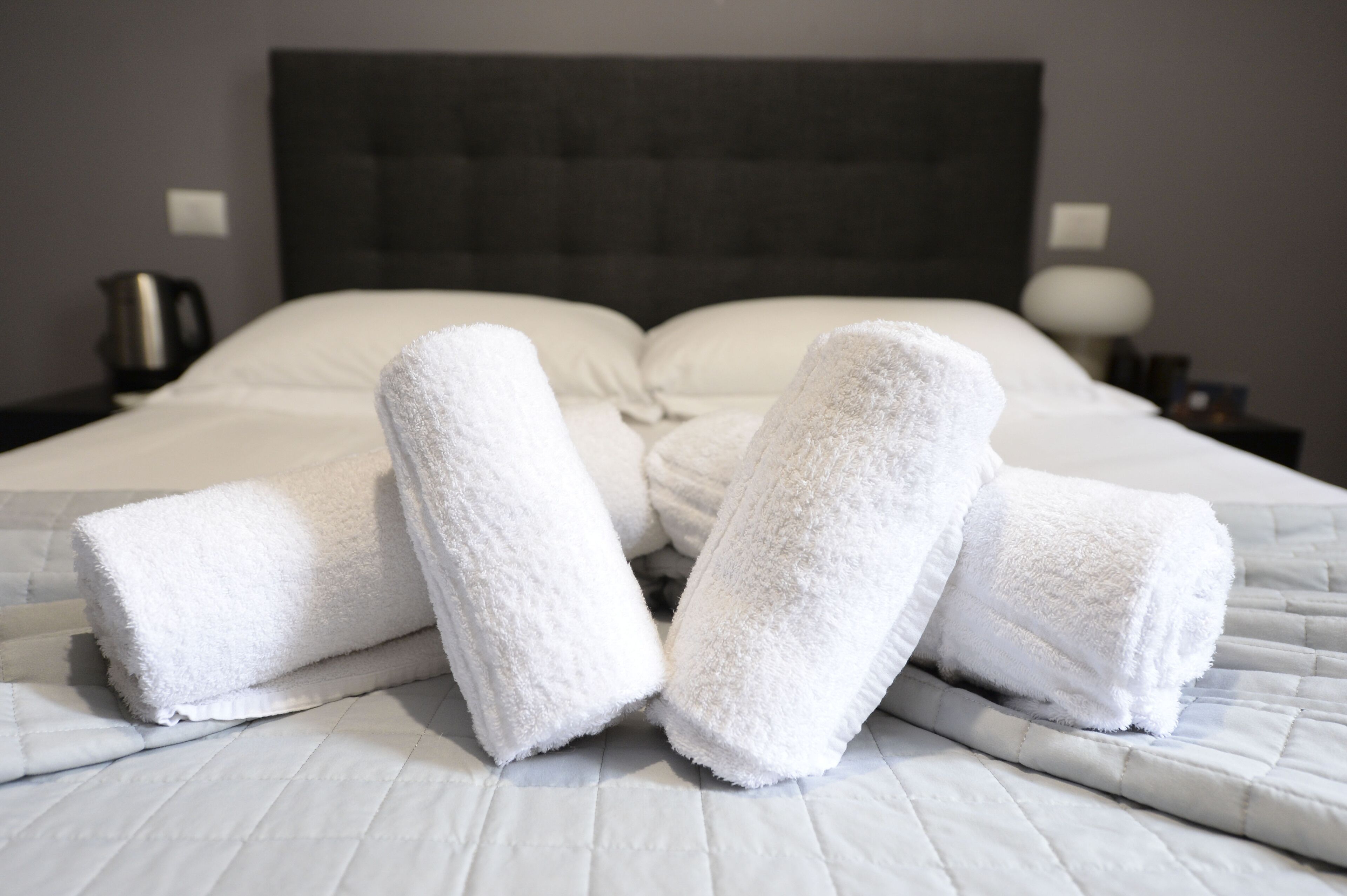 Un lit bien fait, avec du linge de lit blanc et des serviettes enroulées.