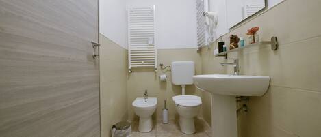 A small, clean bathroom with a toilet, bidet, and sink.
