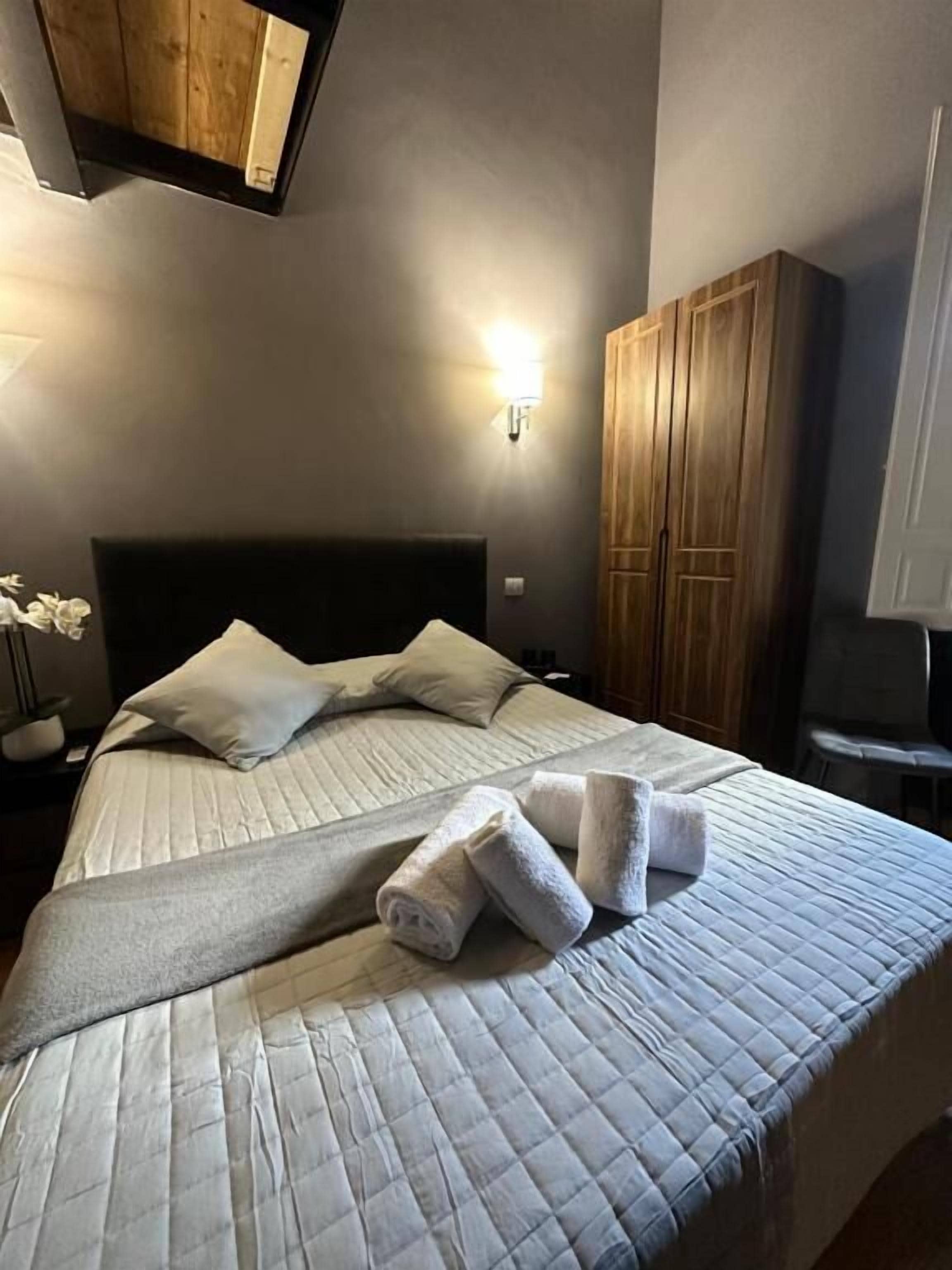 Una cama bien hecha con un edredón acolchado, almohadas y toallas dobladas.