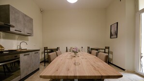 A modern kitchen with a large wooden table, built-in cabinets, and a hanging light fixture. - Palazzo Oliveto (Florence)