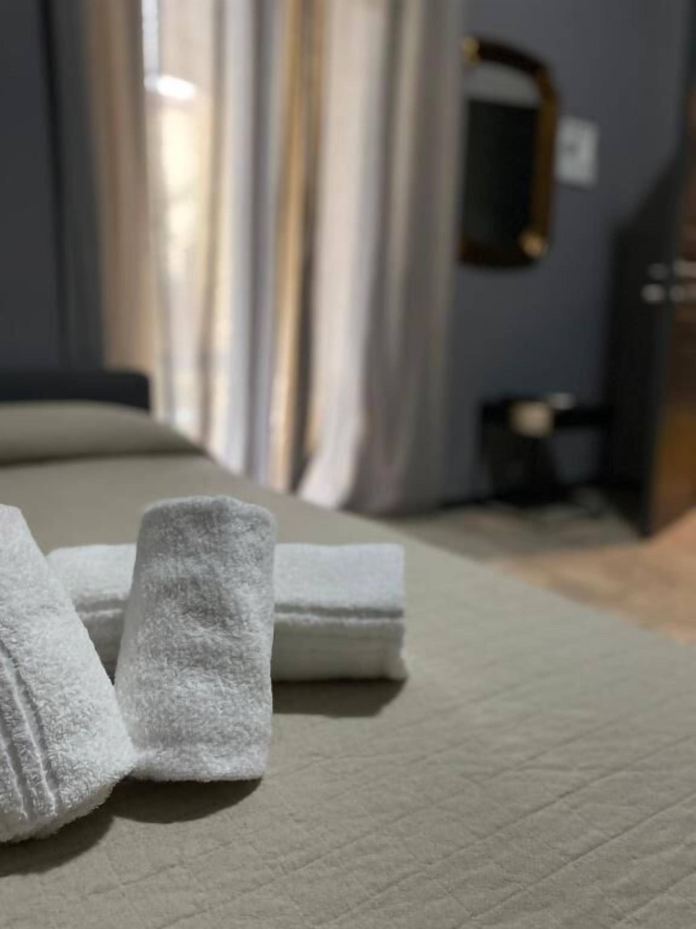 Un lit bien fait, avec des serviettes blanches pliées et une tête de lit bien visible.