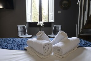 A hotel room with a bed, two chairs, a window with a view, and a vase with flowers. - Palazzo Oliveto (Florence)
