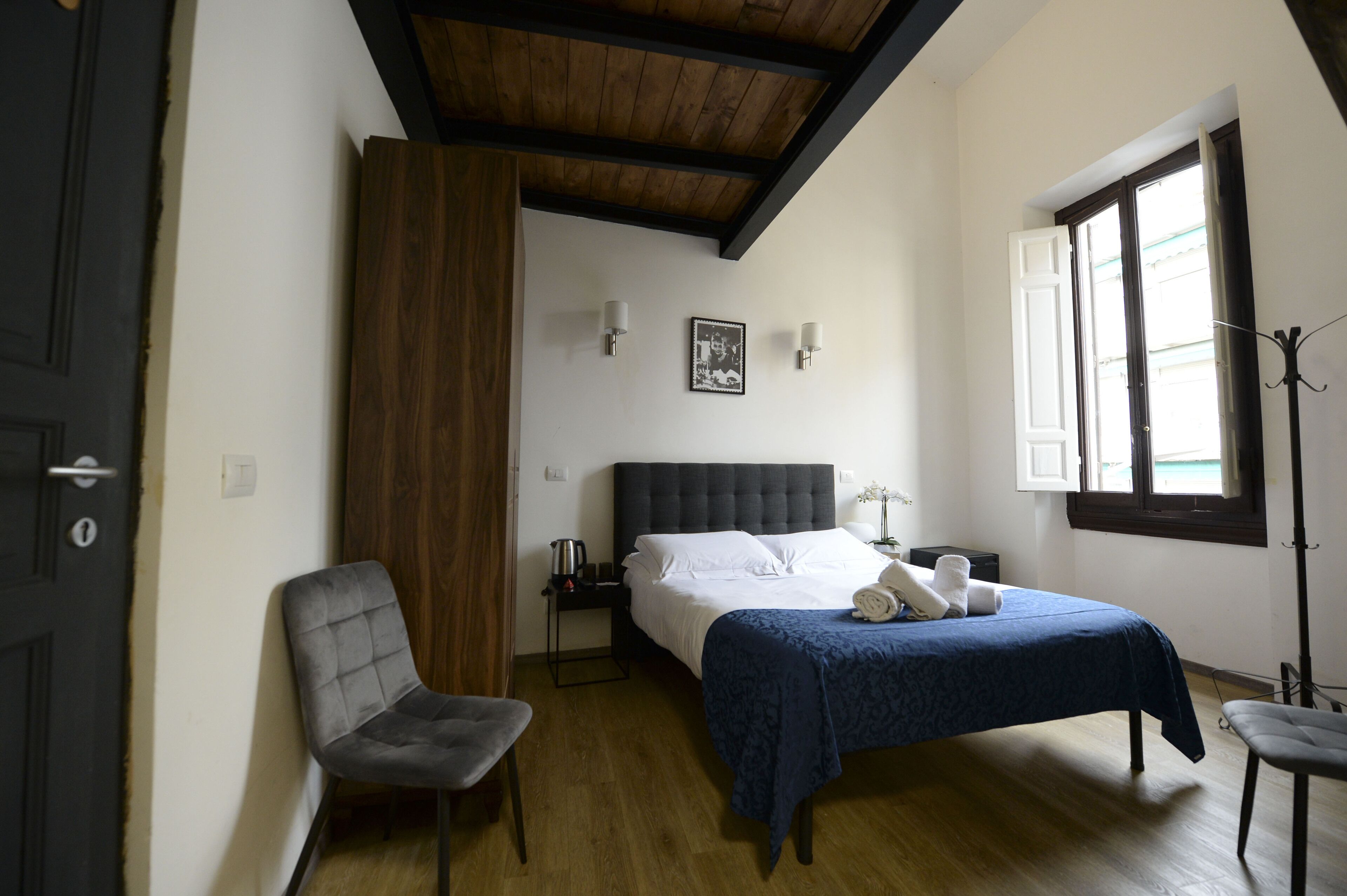Une chambre à coucher avec un lit, une chaise, une table de chevet, une fenêtre et une porte.
