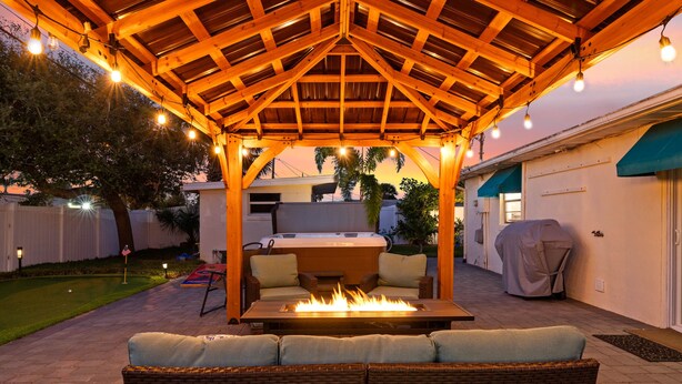 Eine Außenpatio mit einer Holz-Pergola, einem Feuerkorb und Korbmöbeln.