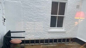 A small, white-walled room with a single window and a stone-tiled floor. - Expansive 4BD Home- 15 min From Buckingham Palace! (London)