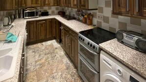 A modern kitchen with wooden cabinets, a microwave, stove, and a washing machine. - Expansive 4BD Home- 15 min From Buckingham Palace! (London)