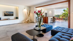 A modern living room with a flat-screen TV, a coffee table, and blue sofas. - Studio-Romantic-Wet room-Sea view-RDC Avec Terrasse privée (La Trinité)
