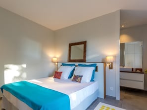 Une chambre d’hôtel avec un lit, des lampes de chevet, un miroir et une salle de bain visible au fond.
