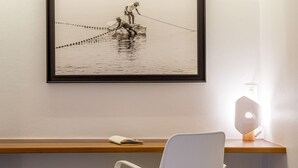 A framed photograph of fishermen on a boat, a white chair, and a table with a lamp. - Studio-Romantic-Wet room-Sea view-RDC Avec Terrasse privée (La Trinité)