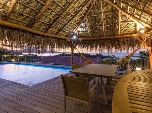 Une terrasse en bois avec une piscine, une table et des chaises.
