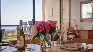 Une table à manger avec des verres à vin, une bouteille et un vase rempli de fleurs.