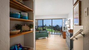 Un vaste espace de vie agrémenté d’un canapé vert, d’étagères en bois et offrant une vue sur un terrain de golf grâce à de grandes portes-fenêtres coulissantes.