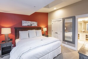 A bedroom with a large bed, two bedside tables with lamps, a wooden headboard, and a painting on the wall. - River Club 306 2 Bedroom Condo by Alpine Lodging Telluride (Telluride)