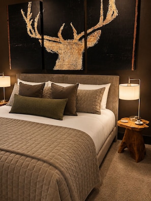 A bedroom with a large bed, two bedside tables, and a wall-mounted artwork of a deer antler. - Bear Creek Lodge 303 3 Bedroom Condo by Alpine Lodging Telluride (Telluride)