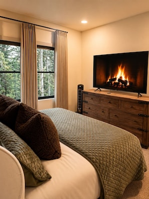 A bedroom with a large bed, a TV mounted above a fireplace, and a window with curtains. - Bear Creek Lodge 303 3 Bedroom Condo by Alpine Lodging Telluride (Telluride)