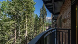 Un edificio in legno con un balcone che si affaccia su una fitta foresta e una montagna sullo sfondo.