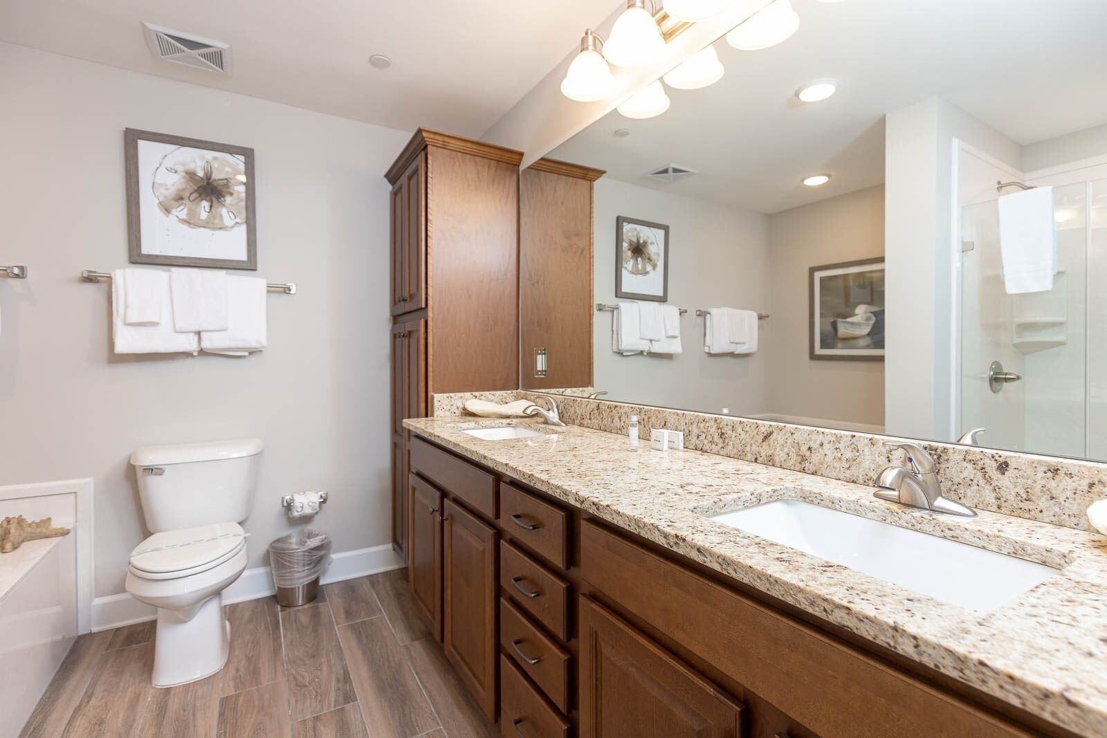 A modern bathroom with a double sink vanity, wooden cabinets, and a large mirror.