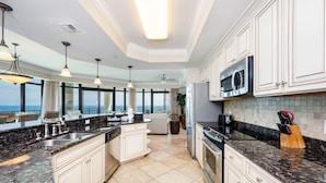 Una cocina moderna con armarios blancos, encimeras de granito y una isla grande.