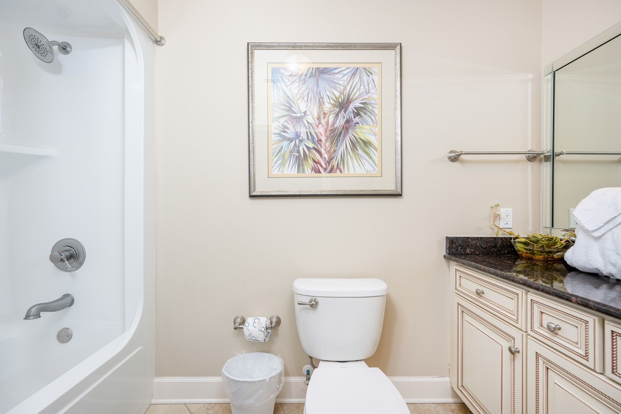 A bathroom with a bathtub, toilet, and vanity with a mirror.