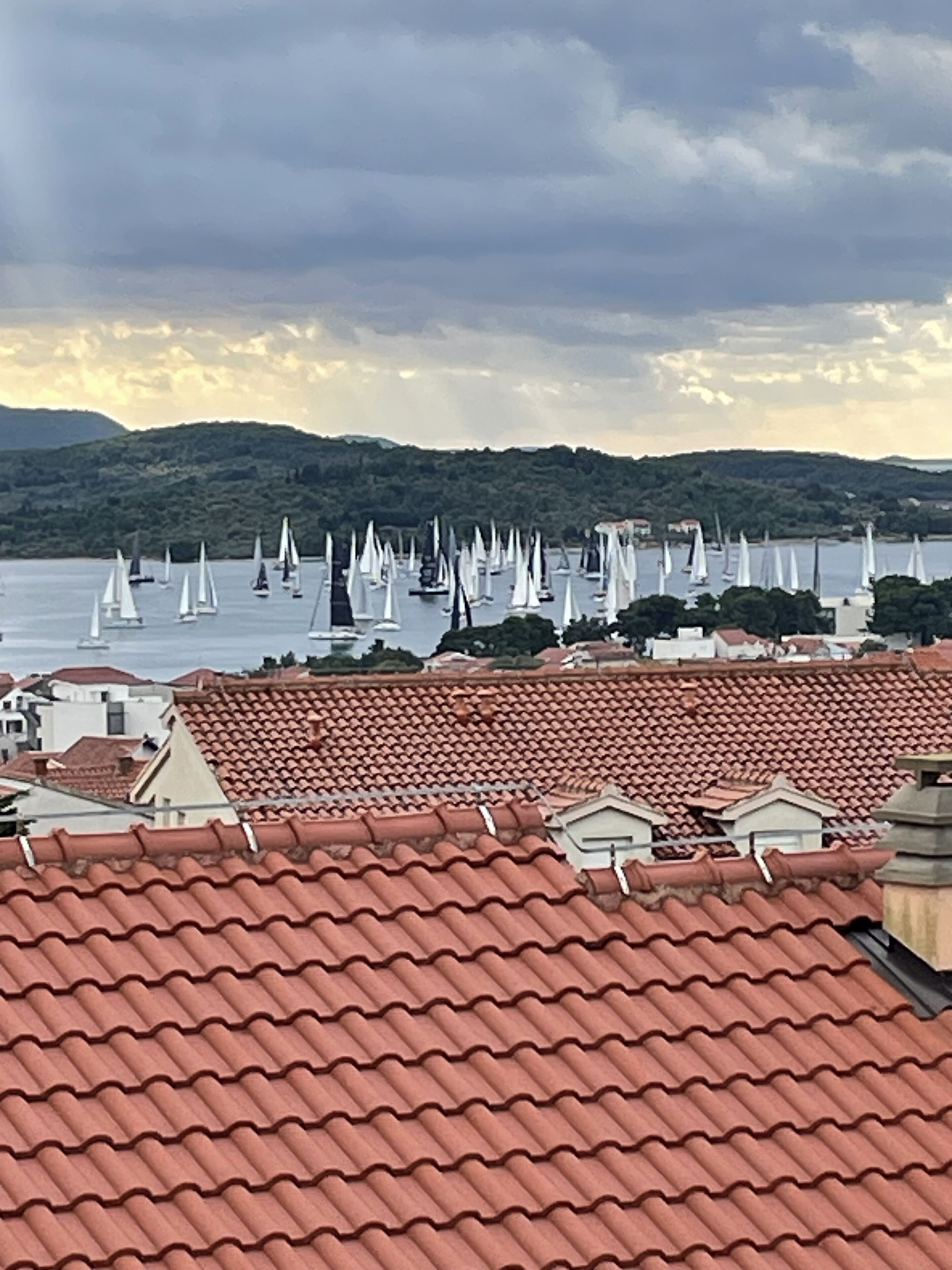 A coastal town with red-tiled roofs and sailboats on the water.