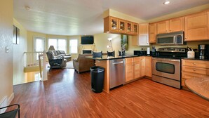 A spacious kitchen with wooden cabinets, a stainless steel oven, and a dining area with a sofa and chairs. - Unit 109 2 Bdrm/ 2 Ba 2 Bedroom Condo by RedAwning (Birchwood)