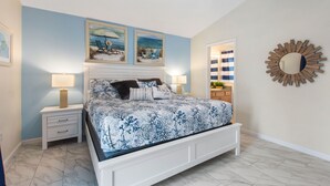 Un dormitorio con cama, mesitas de noche, ventilador de techo y obras de arte en las paredes.