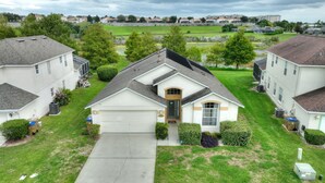 Una casa suburbana con garaje, rodeada de césped y árboles bien cuidados.